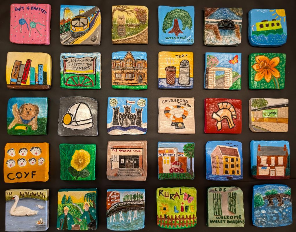 Colourful Clay Tiles depicting buildings, hobbies and memories associated with castleford. This artwork is by Rhiannon Kendall and is titled Our Stories